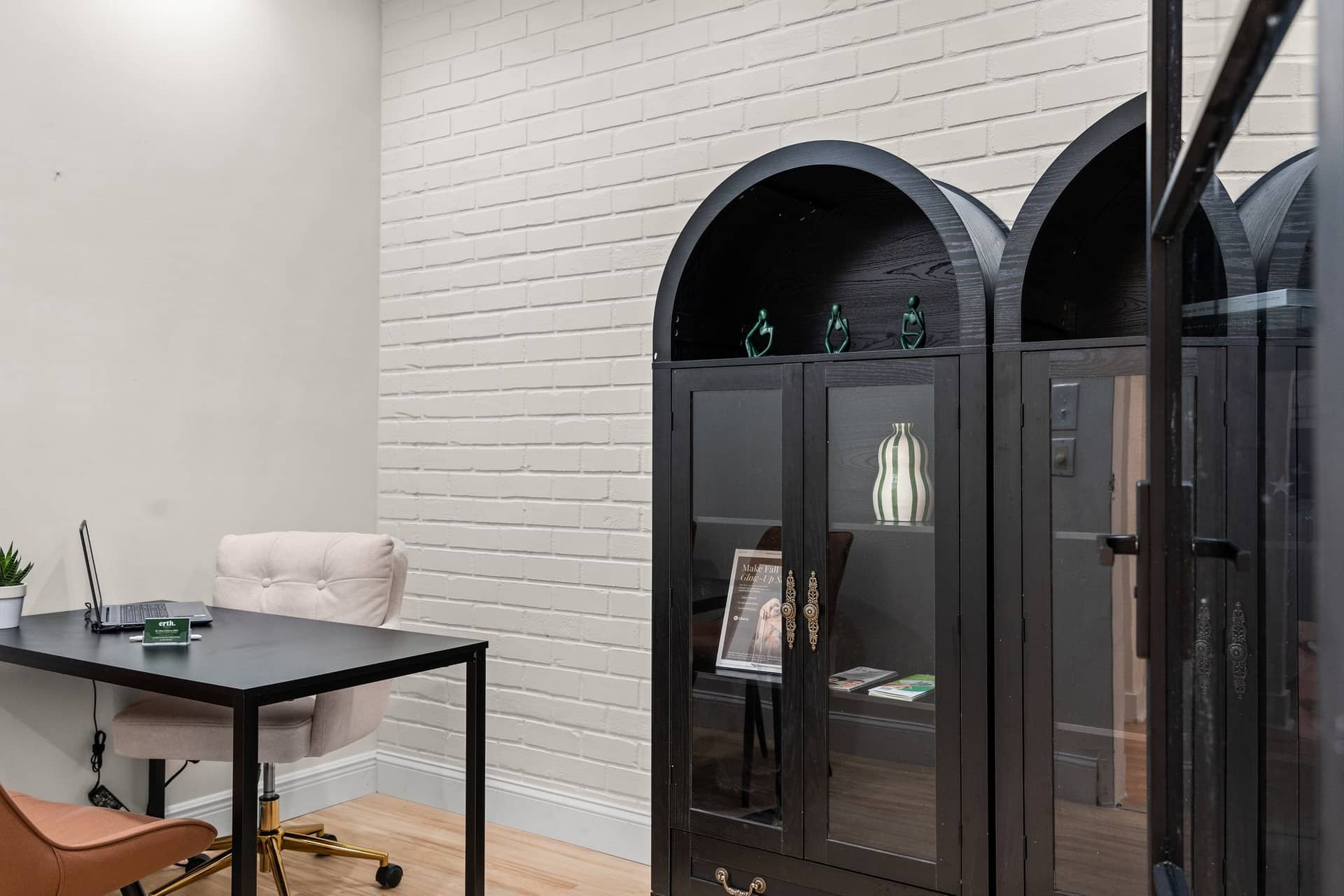 A consultation room at erth. dental with a desk and arched black cabinets