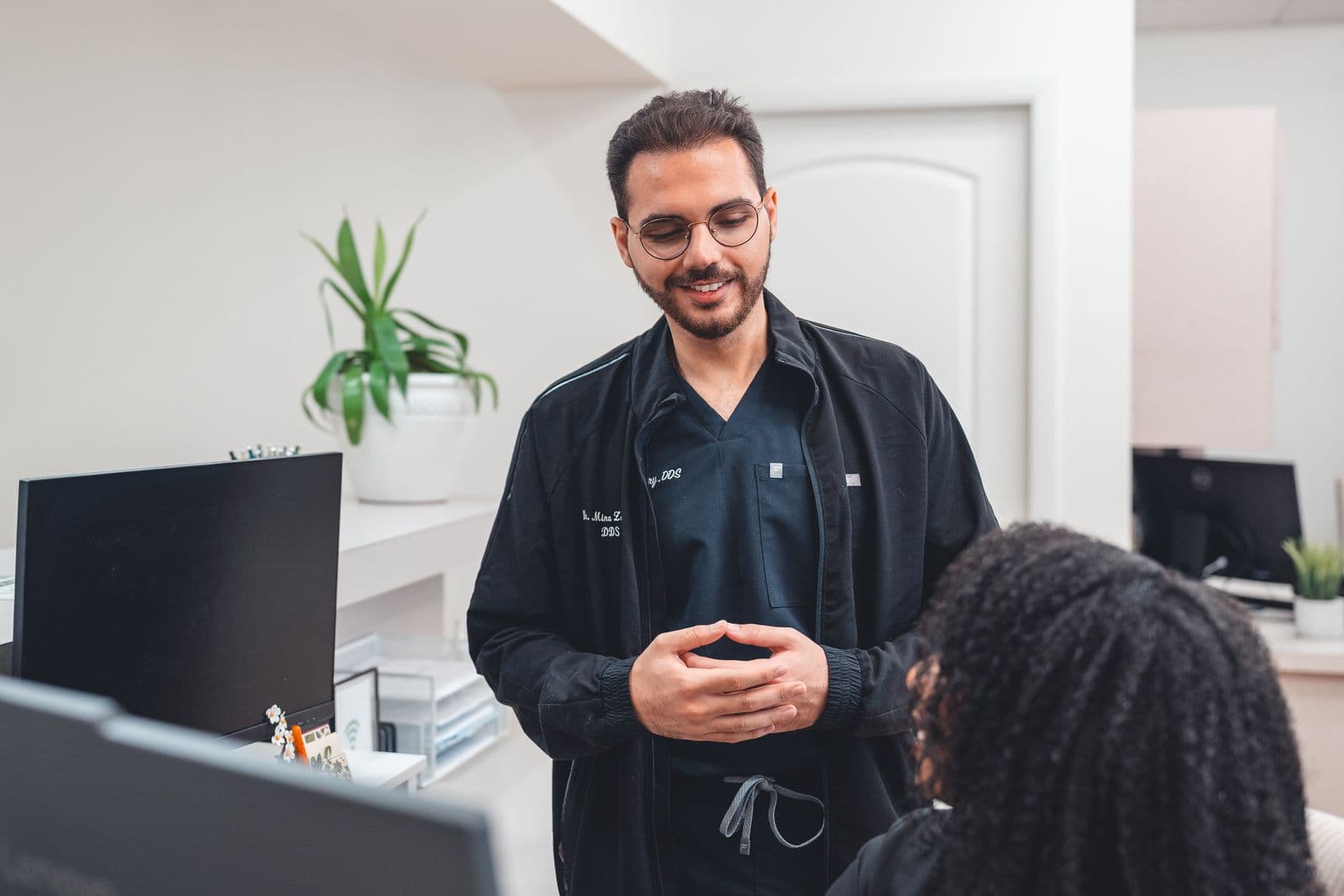 Dr. Mina Zakhary talking with a team member at the front desk