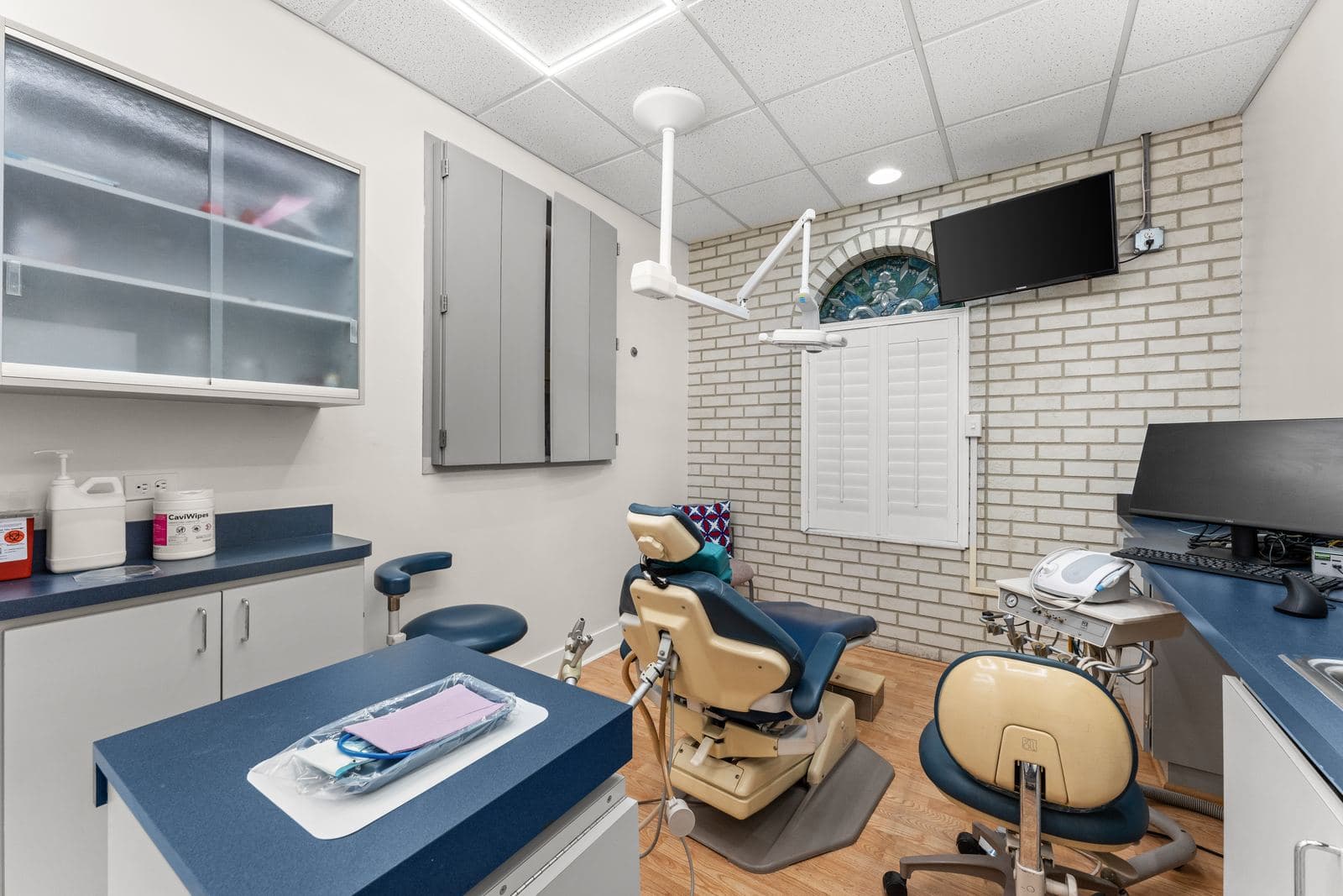 A treatment room at erth. dental with a dental chair beside a white brick wall