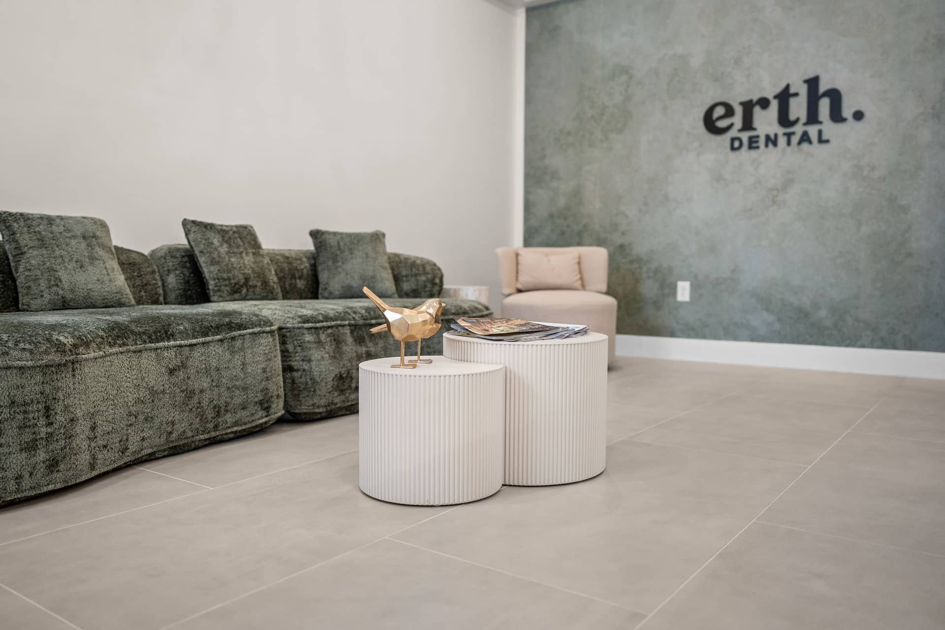 The erth. dental lounge with a green velvet sofa and the erth. dental logo on a plaster wall